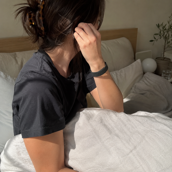 Person sitting up calmly in bed, morning light, Deep Pulse Band visible on wrist